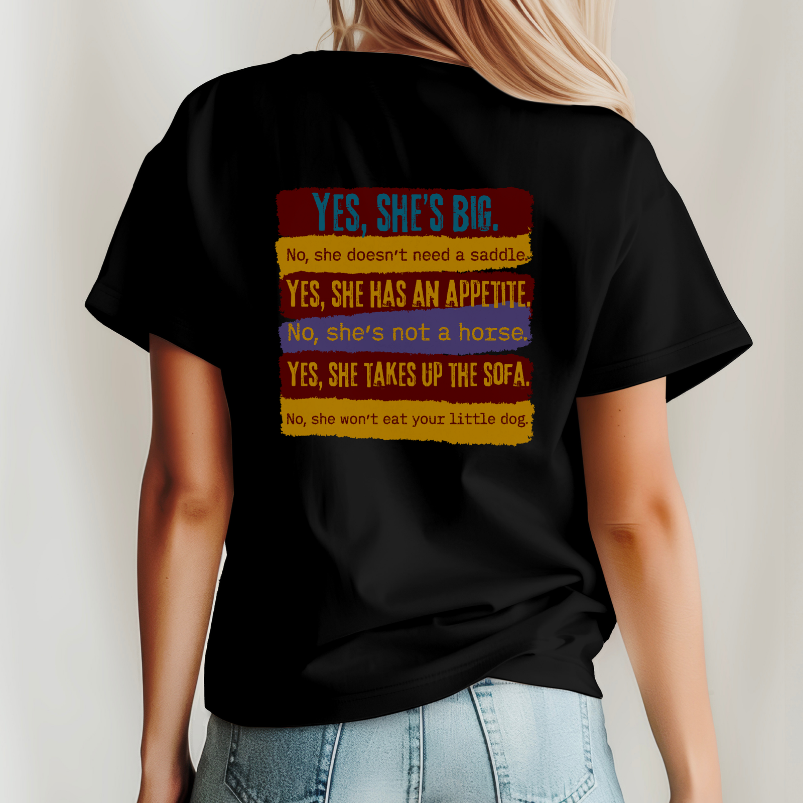 Black t-shirt with colorful text on the back worn by a person, against a plain background